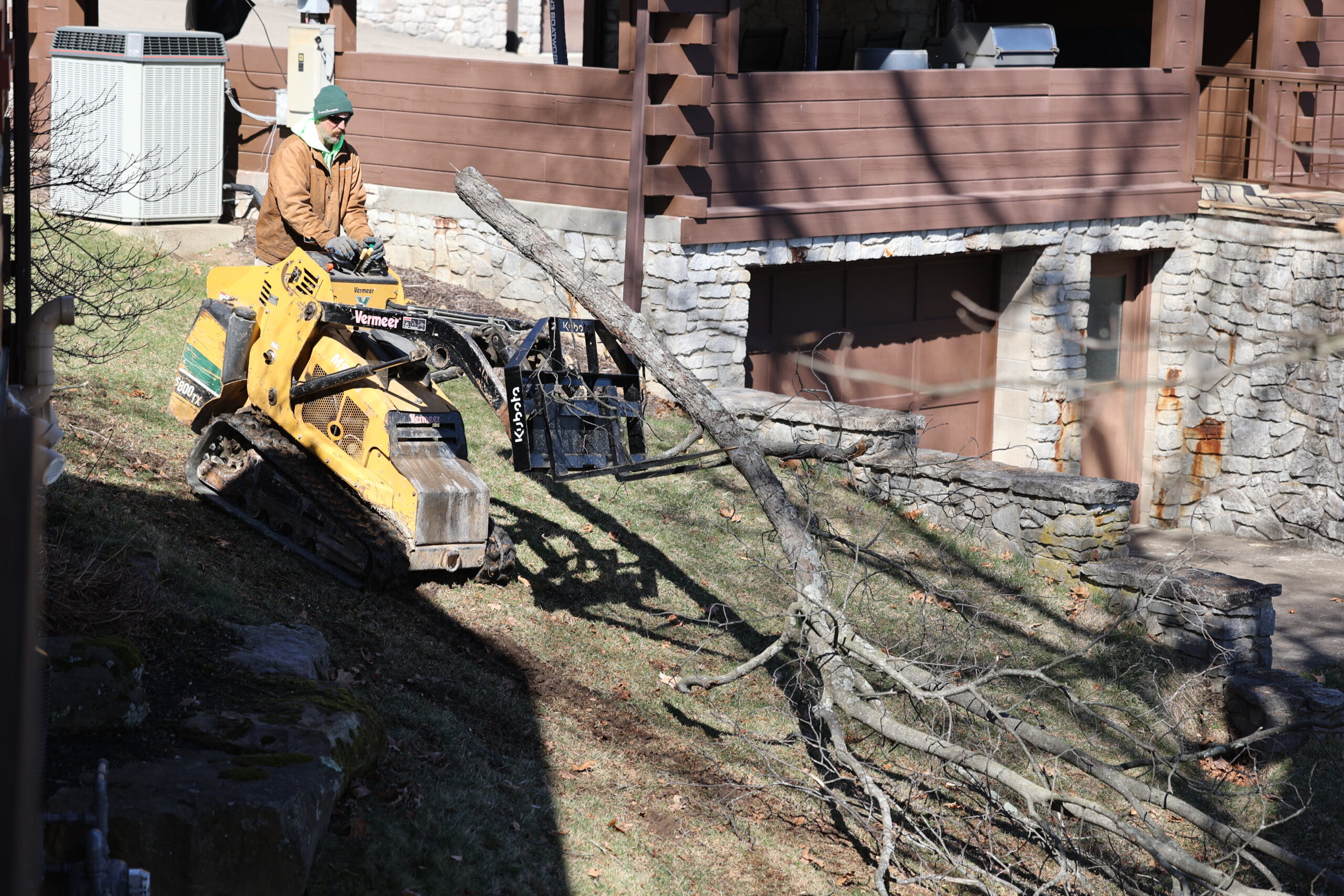Worker on skid steer removing tree branches
